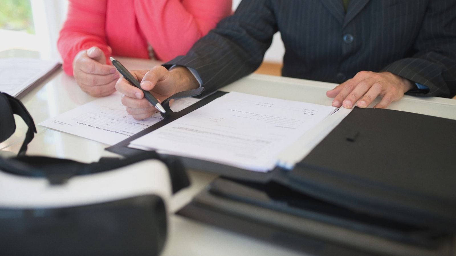 Close-up of professionals signing a business contract indoors, emphasizing agreement and documentation.