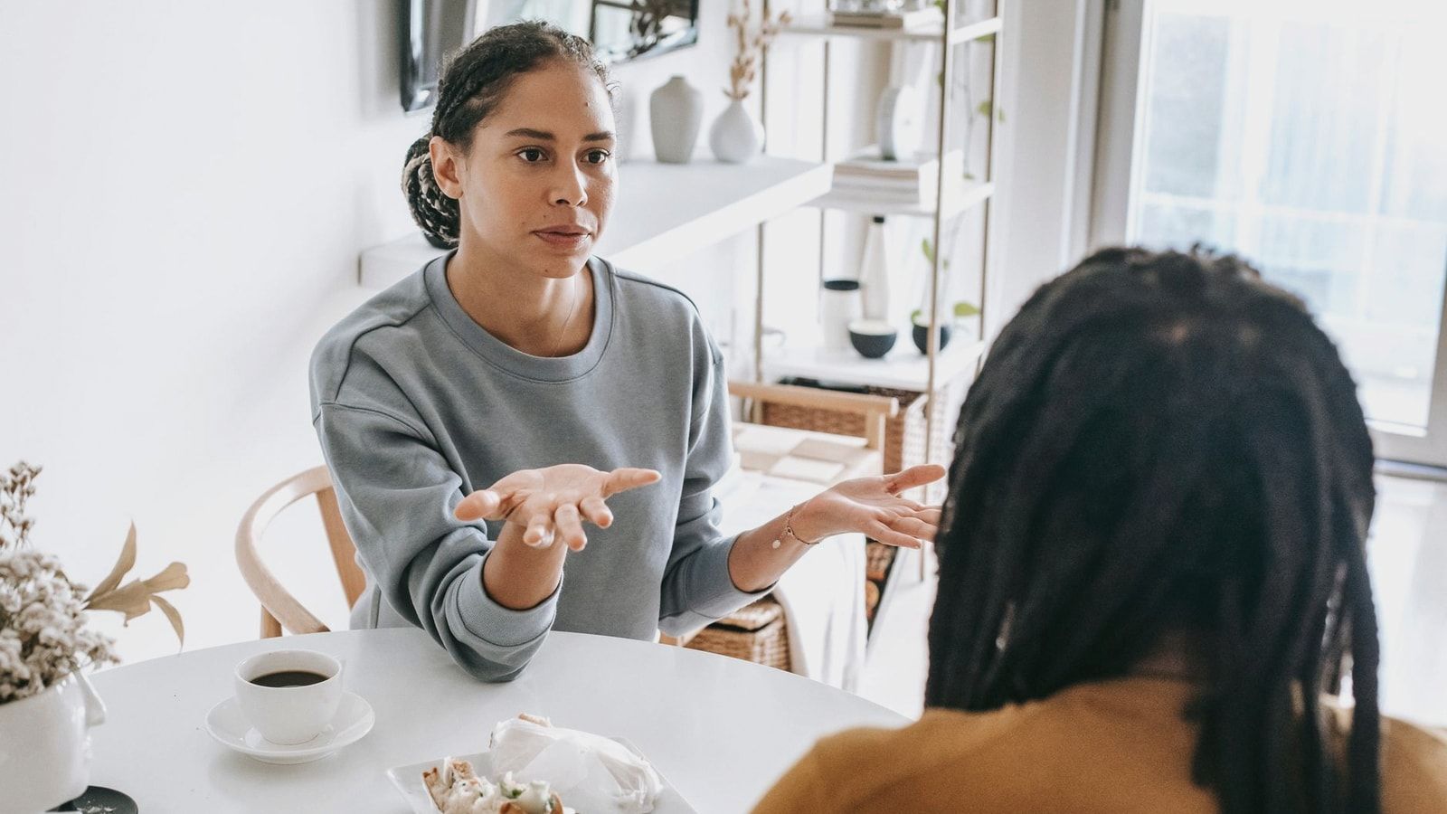Young African American woman sitting at table and arguing with man in casual outfit in daylight