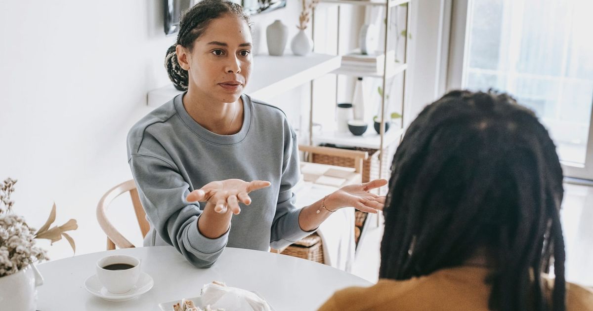 Young African American woman sitting at table and arguing with man in casual outfit in daylight