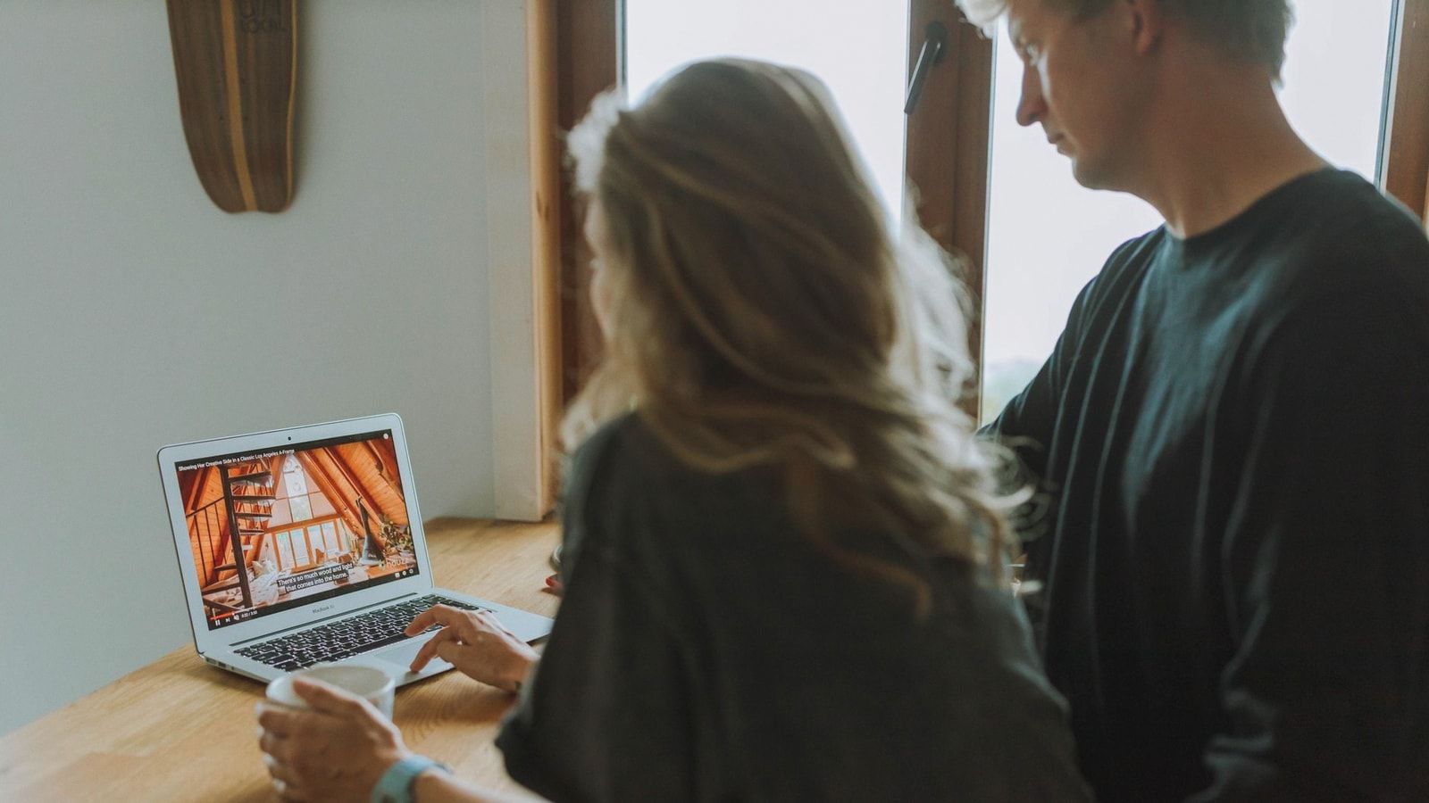 A couple viewing home interior design on a laptop while enjoying coffee together indoors.