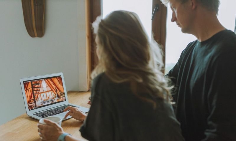 A couple viewing home interior design on a laptop while enjoying coffee together indoors.