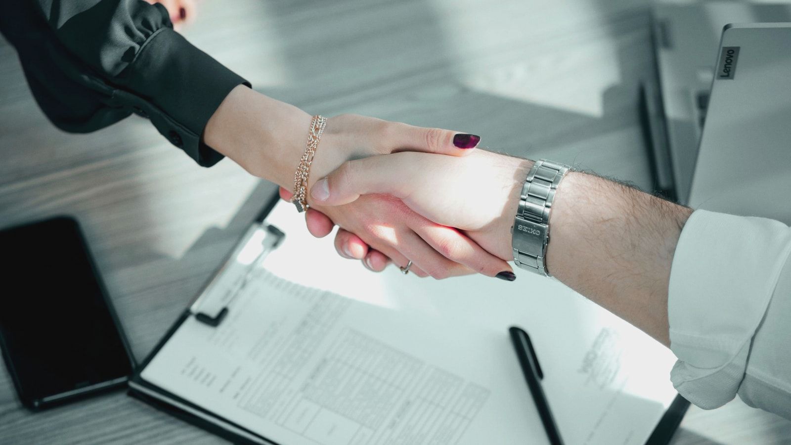 Close-up of a professional handshake over a contract, symbolizing a successful business deal.