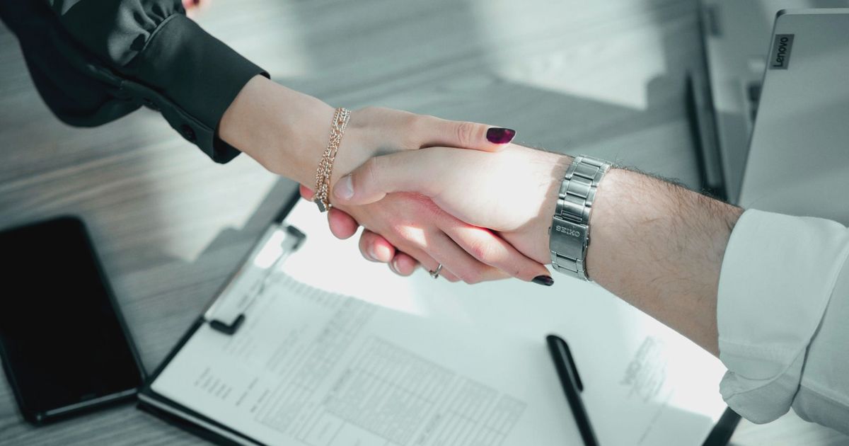 Close-up of a professional handshake over a contract, symbolizing a successful business deal.