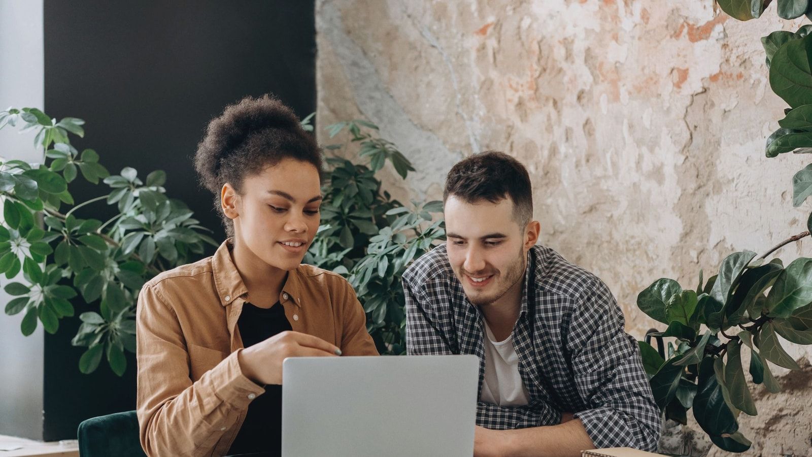 Two colleagues collaborating on a laptop in a stylish indoor workspace.