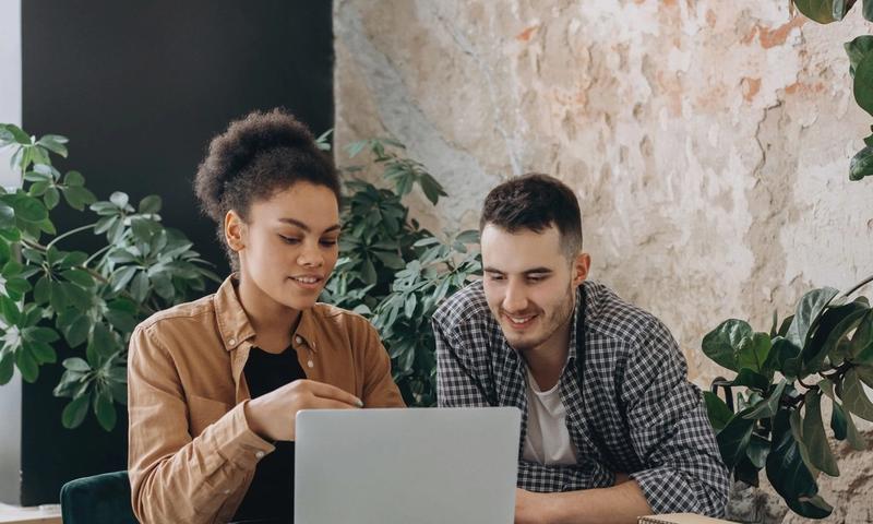 Two colleagues collaborating on a laptop in a stylish indoor workspace.