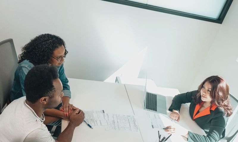 Diverse group discussing business documents in a bright, modern office setting.