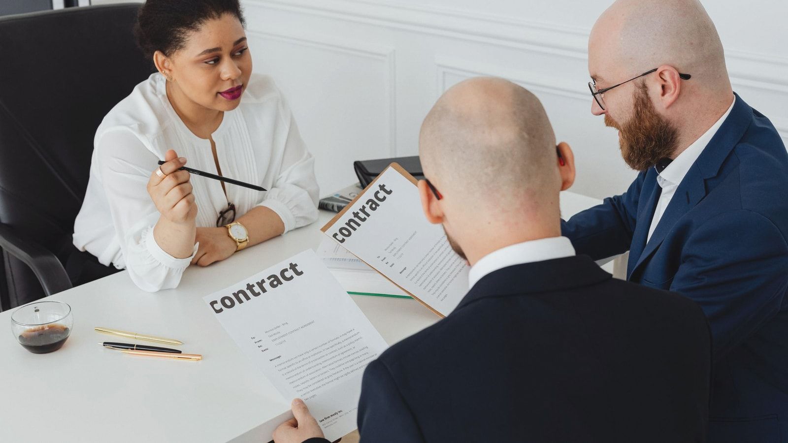 Three business professionals in discussion over a contract in a modern office setting.