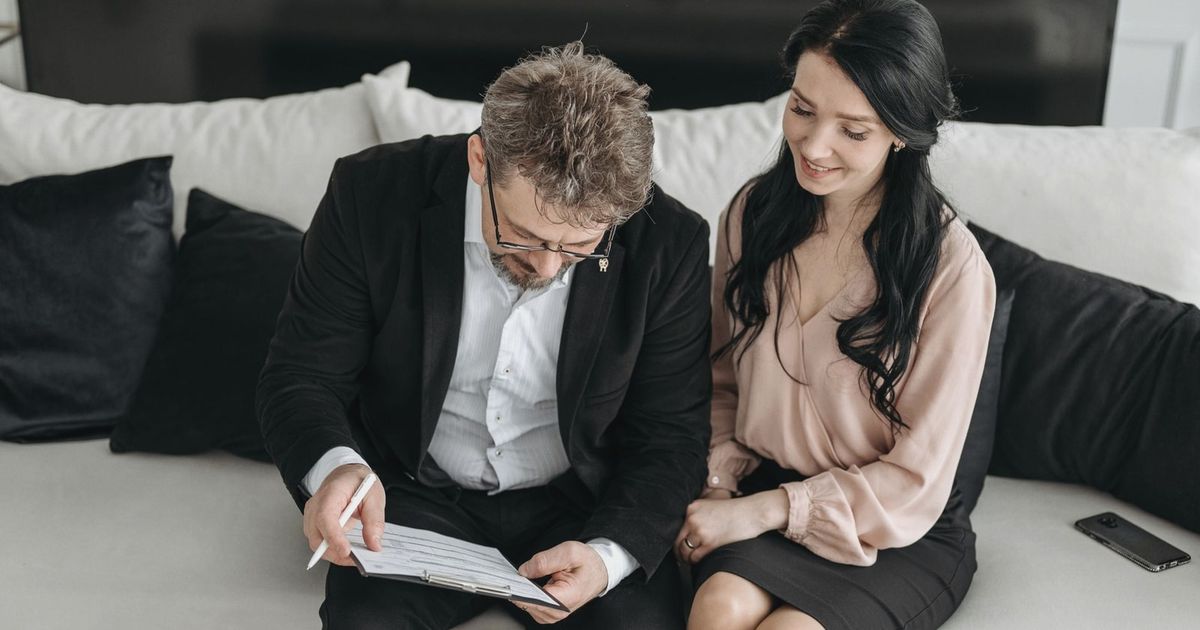Business couple reviewing documents together on a couch, highlighting teamwork and success indoors.