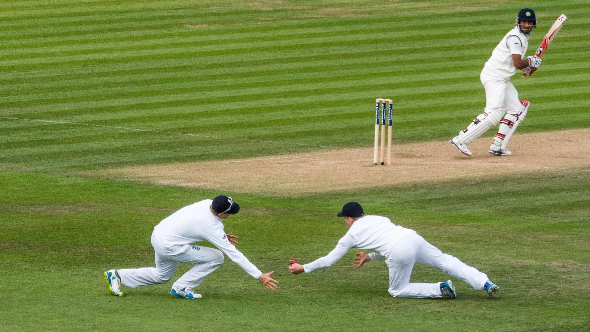 Two England fielders in Test whites dive for a low catch as the batter edges the ball during a Test match in Southampton
