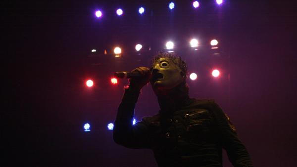Corey Taylor of Slipknot singing in silhouette in front of a wall of red, white and blue stage lights