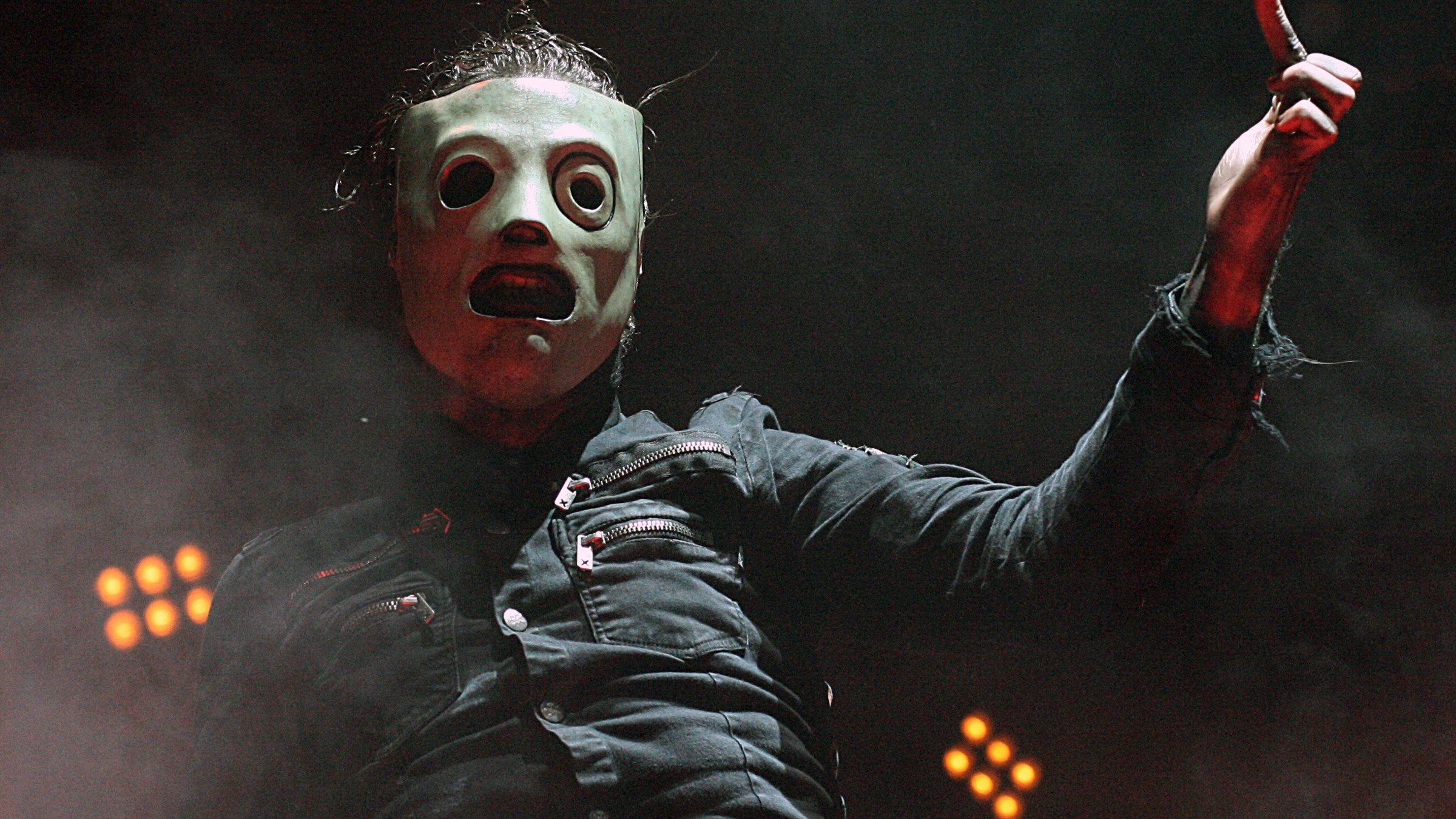 Corey Taylor of Slipknot in his mask and dark jacket, pointing out towards the crowd on stage