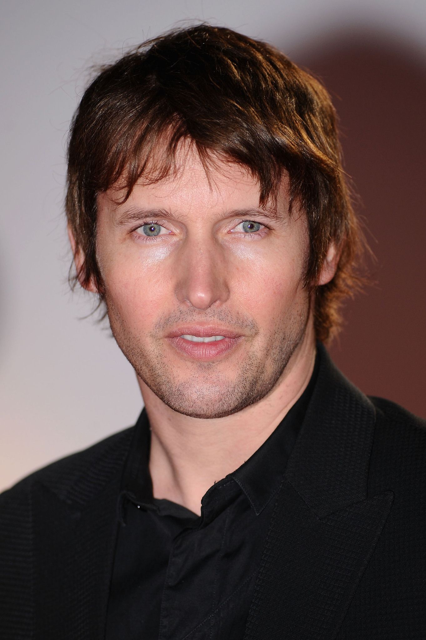 Head and shoulders portrait of James Blunt in a black jacket and open black shirt
