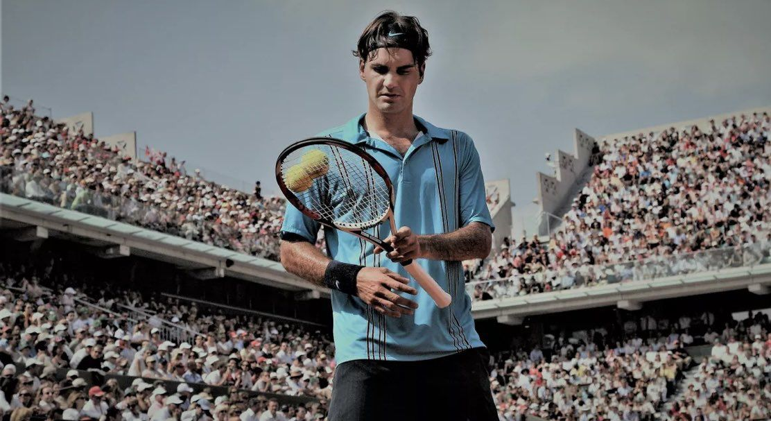 Roger Federer playing tennis, focused with Nike gear, before a stadium full of fans.