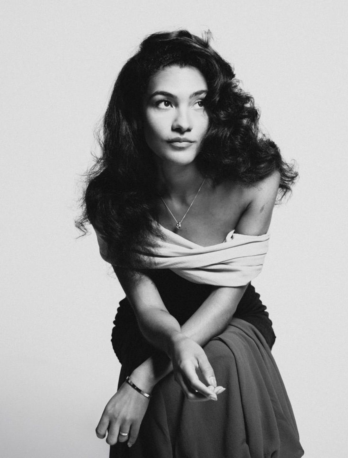 Thoughtful actress in black and white studio portrait with wavy hair, bare shoulders.