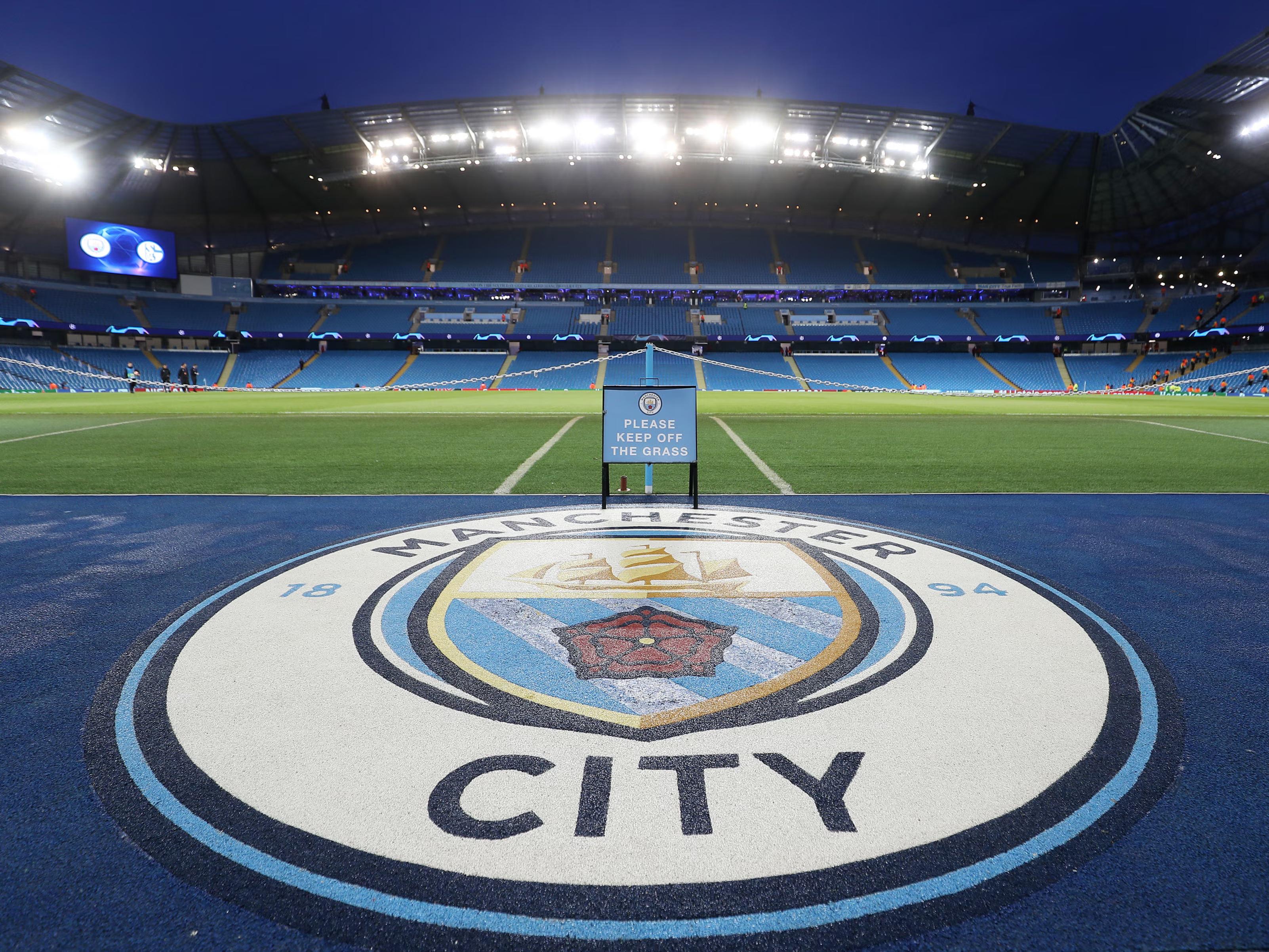 Manchester City hospitality crest at Etihad Stadium under lights for a Champions League matchday.