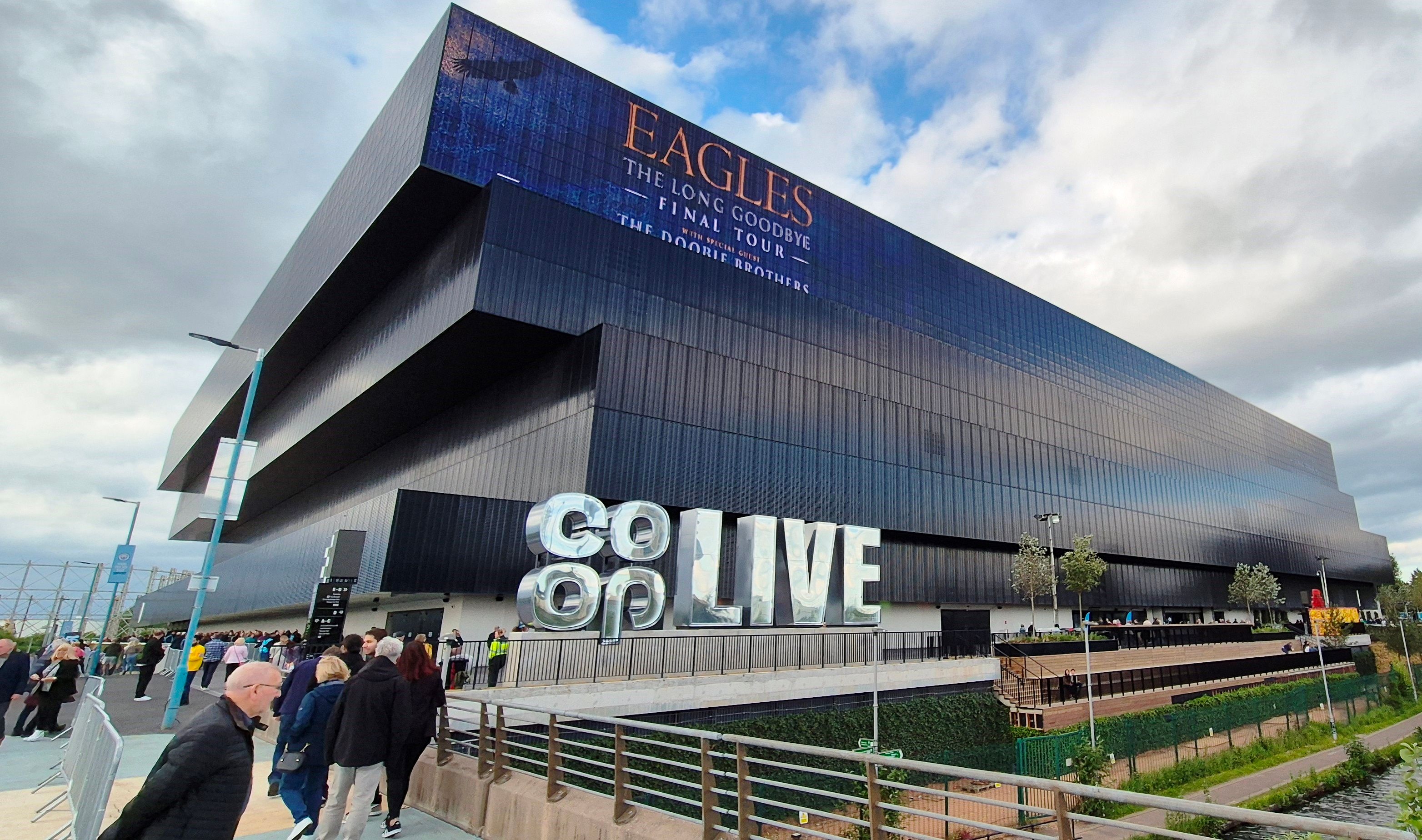 Exterior of Co-op Live arena in Manchester with its large lettered sign and people walking past, June 2024