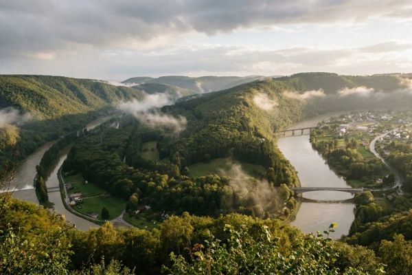 Dense Ardennes forest and rolling green hills around Spa-Francorchamps, clearing after rain