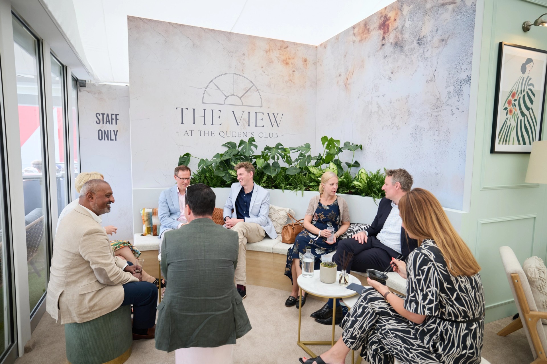 Guests chat on sofas in The View lounge with green plants and framed art