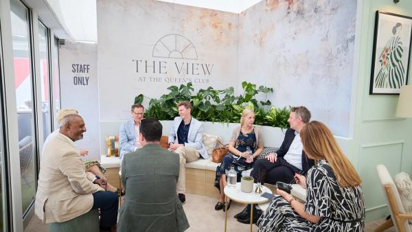 Guests chat on sofas in The View lounge with green plants and framed art