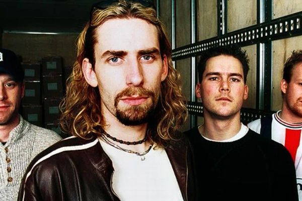 An older Nickelback band photo, Chad Kroeger with long hair and a brown leather jacket at the front