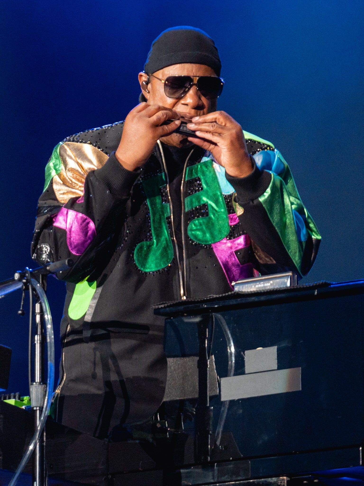 Stevie Wonder playing the harmonica on stage under blue lights