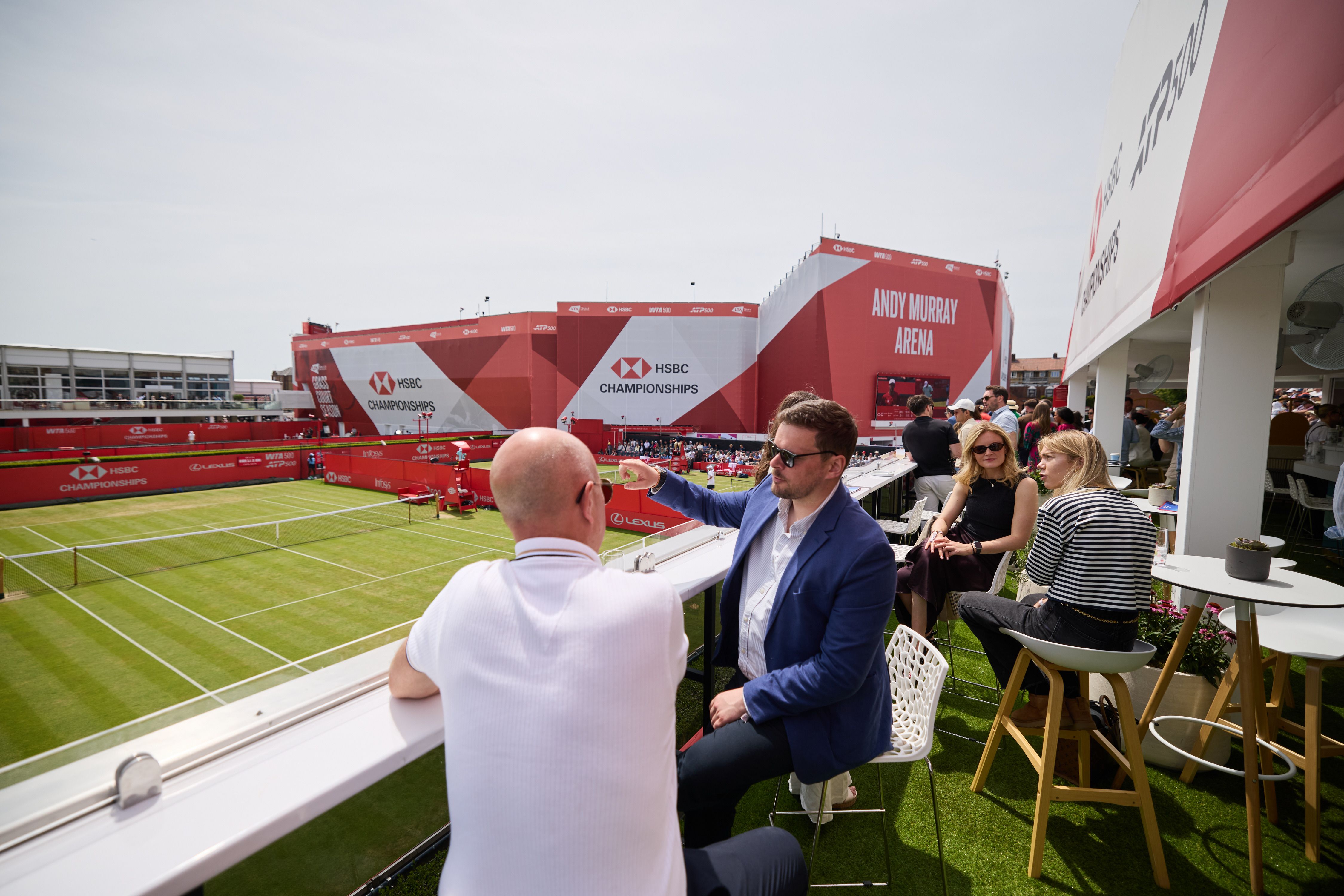 Guests relax on a terrace bar overlooking the courts