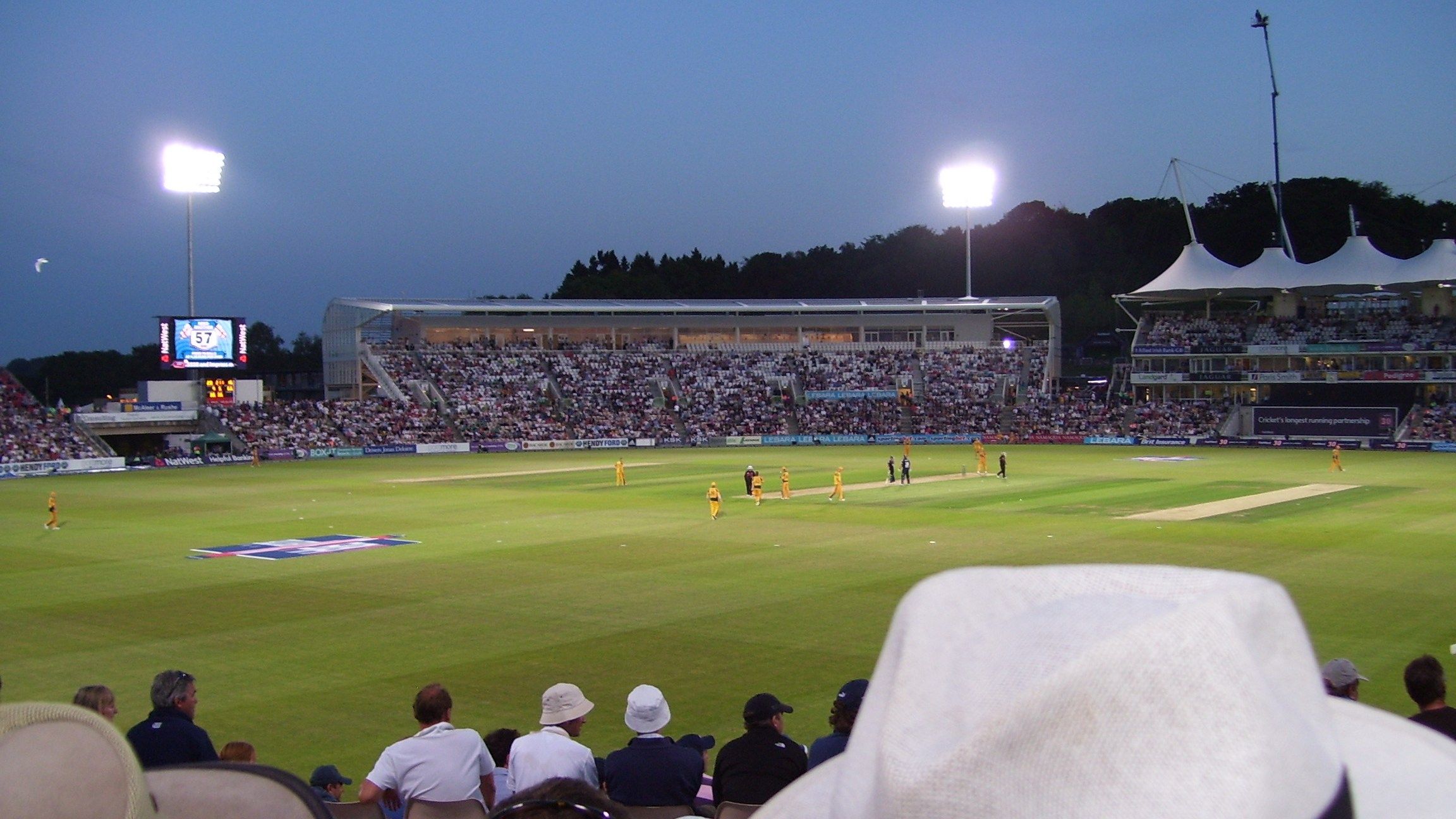 Australia, in yellow, fielding against England under floodlights at the Southampton ground now called the Utilita Bowl, with spectators watching from the front rows