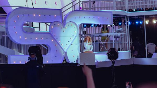 Sabrina Carpenter singing in a white sequinned outfit in front of a giant lit SC heart sign at BST Hyde Park in London, July 2025