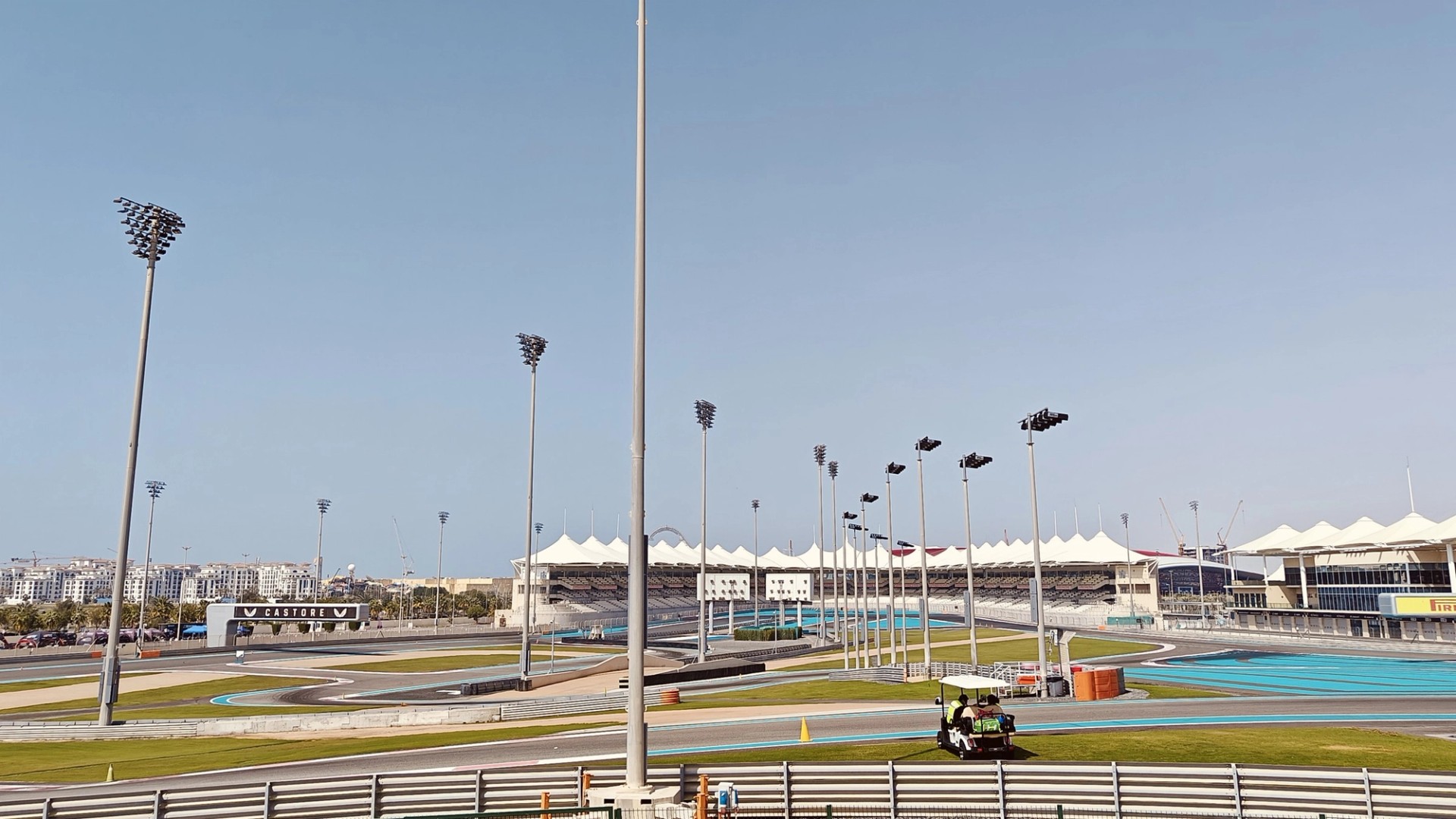 The North Grandstand and its white canopy roof at Yas Marina Circuit in Abu Dhabi on a clear day, with floodlight towers above the empty track