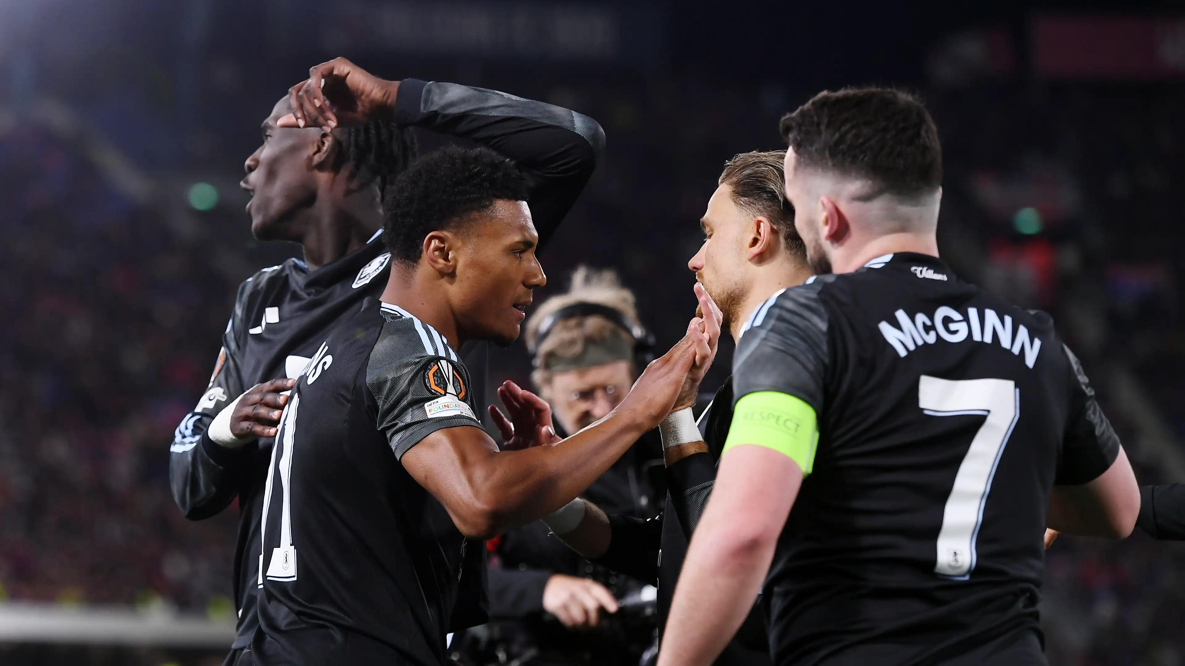 Aston Villa hospitality guests watch McGinn and teammates in an intense Europa League match huddle.
