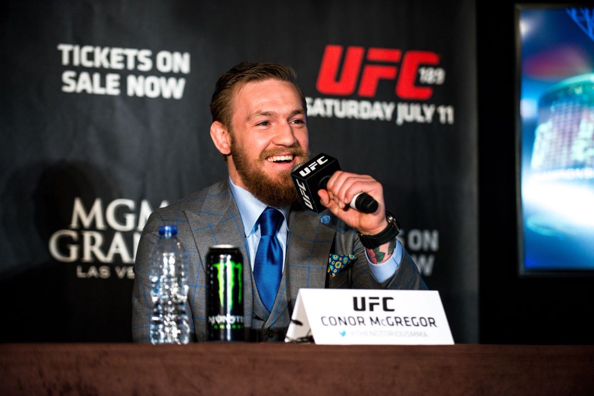 Conor McGregor smiling and holding a microphone at a UFC press event in London in March 2015
