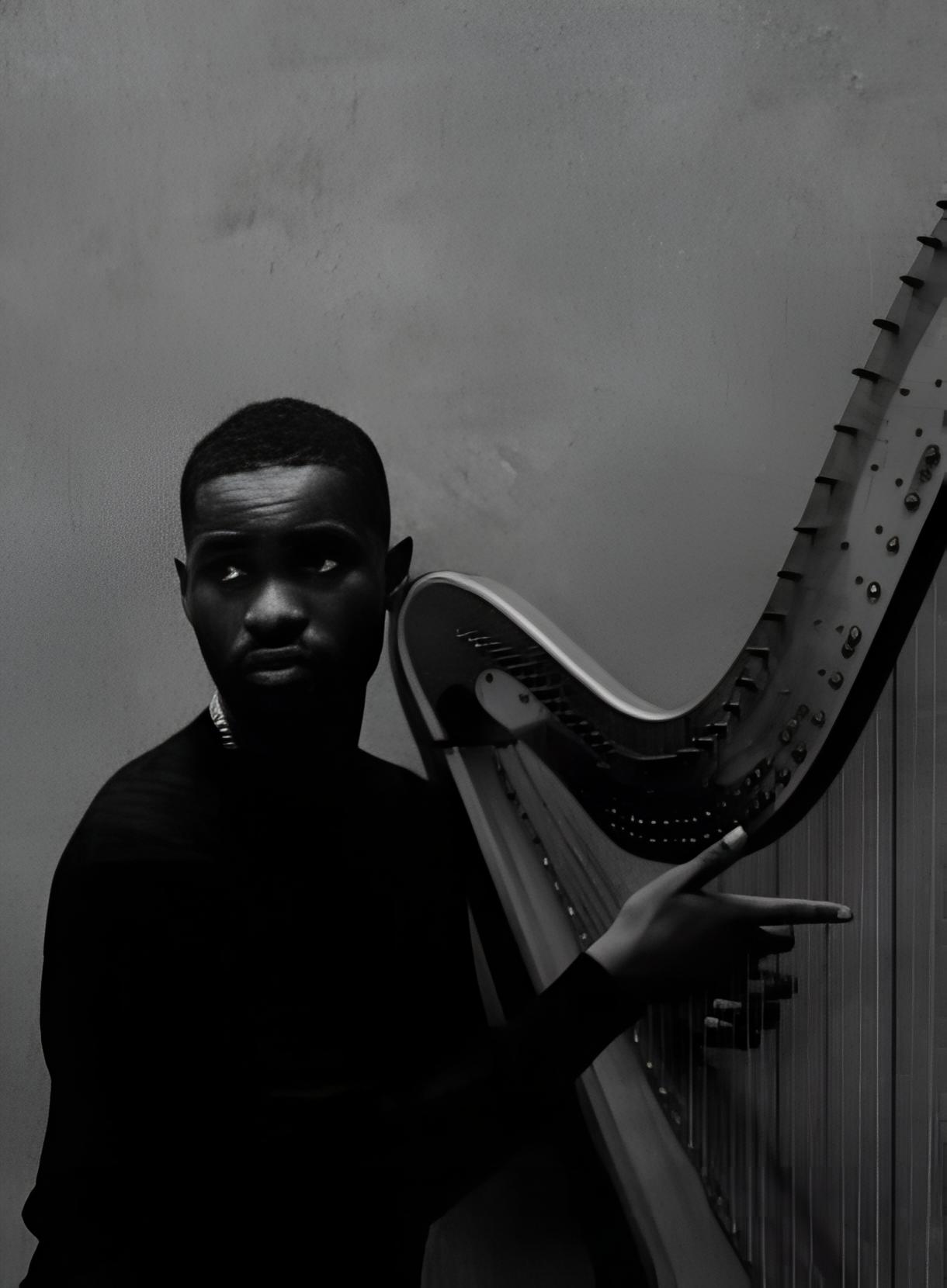 Black and white close-up of a serious male harpist performing with a classical pedal harp.