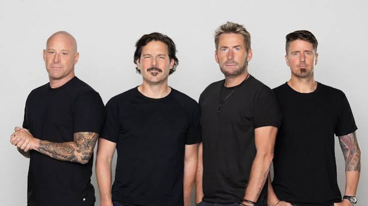 The four members of Nickelback standing in a row in black T-shirts against a light grey backdrop