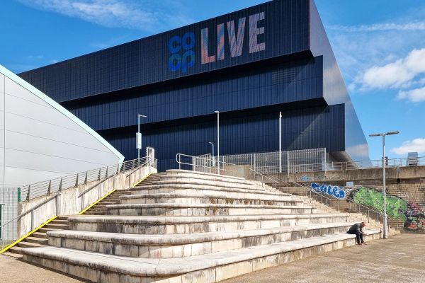 Co-op Live arena in Manchester seen from wide stone steps under a blue sky, September 2024