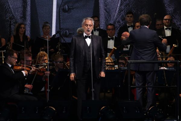 Andrea Bocelli on stage with an orchestra and a choir behind him at a concert in Gibraltar in 2019