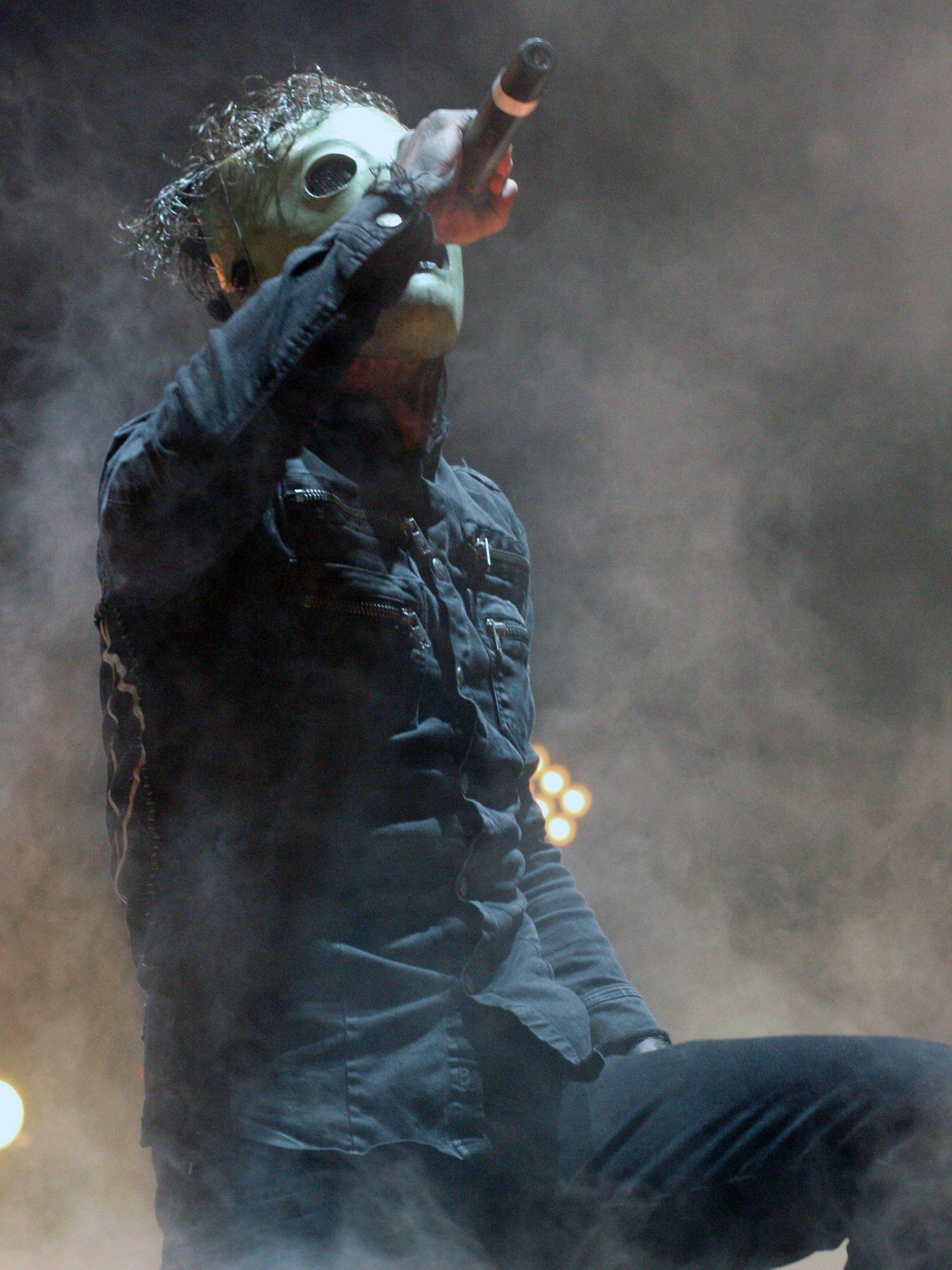 Corey Taylor of Slipknot pointing his microphone at the crowd through stage smoke