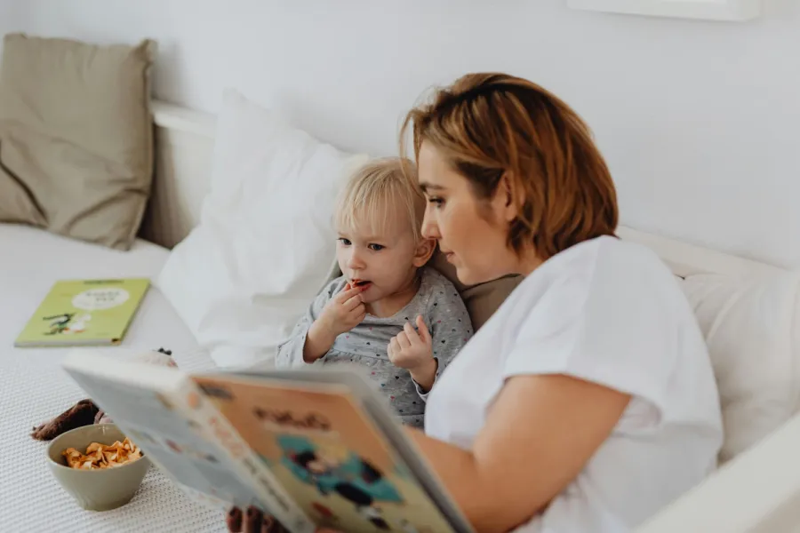 zdjęcie przedstawiające mamę czytającą małemu dziecku bajkę, mama i synek siedzący na kanapie