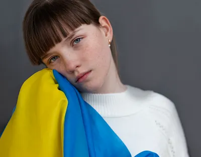 smutna dziewczynka trzymająca przy twarzy flagę Ukrainy