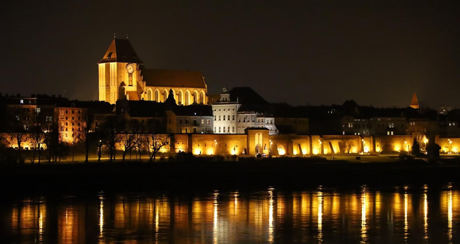 Panorama Torunia nocą od strony Wisły, podświetlone mury i kościoły