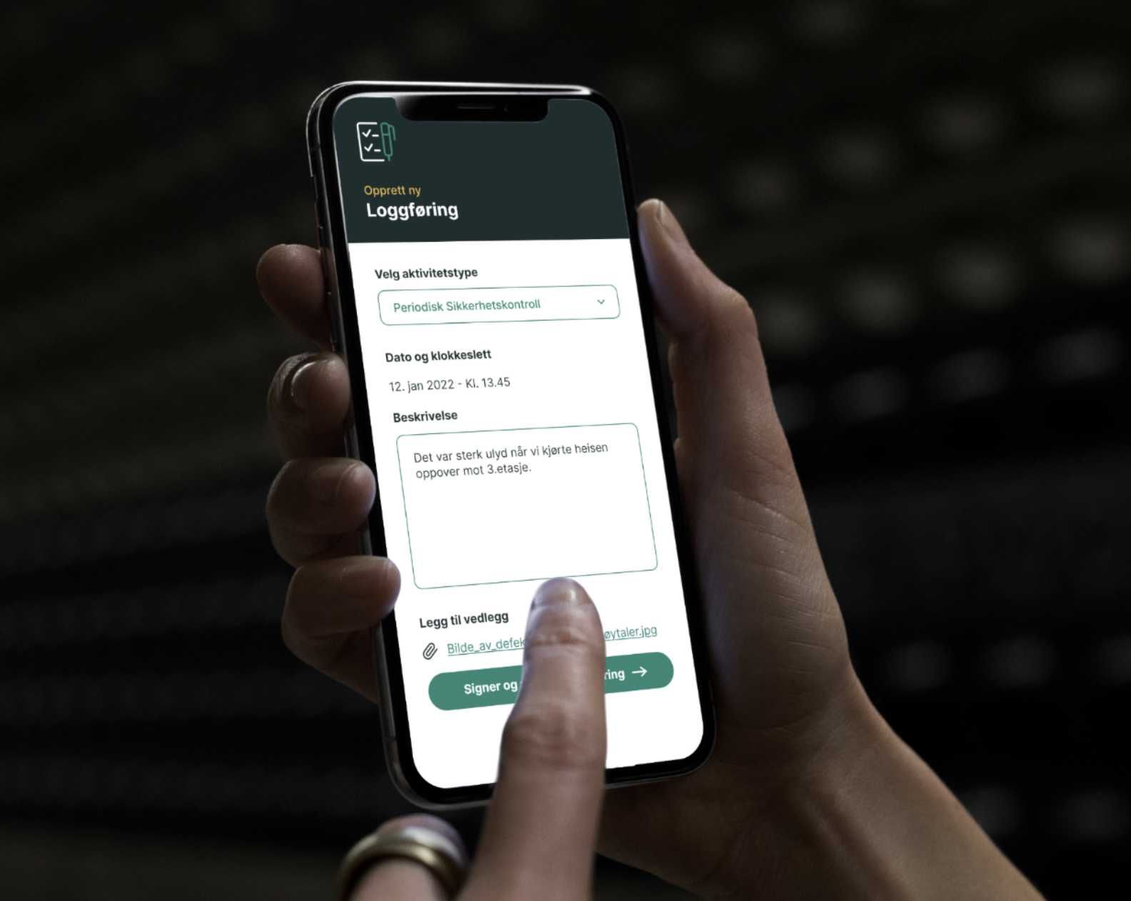 Hånd holder en mobil som viser Lilo-appen, skjema for å logge en periodisk sikkerhetskontroll.