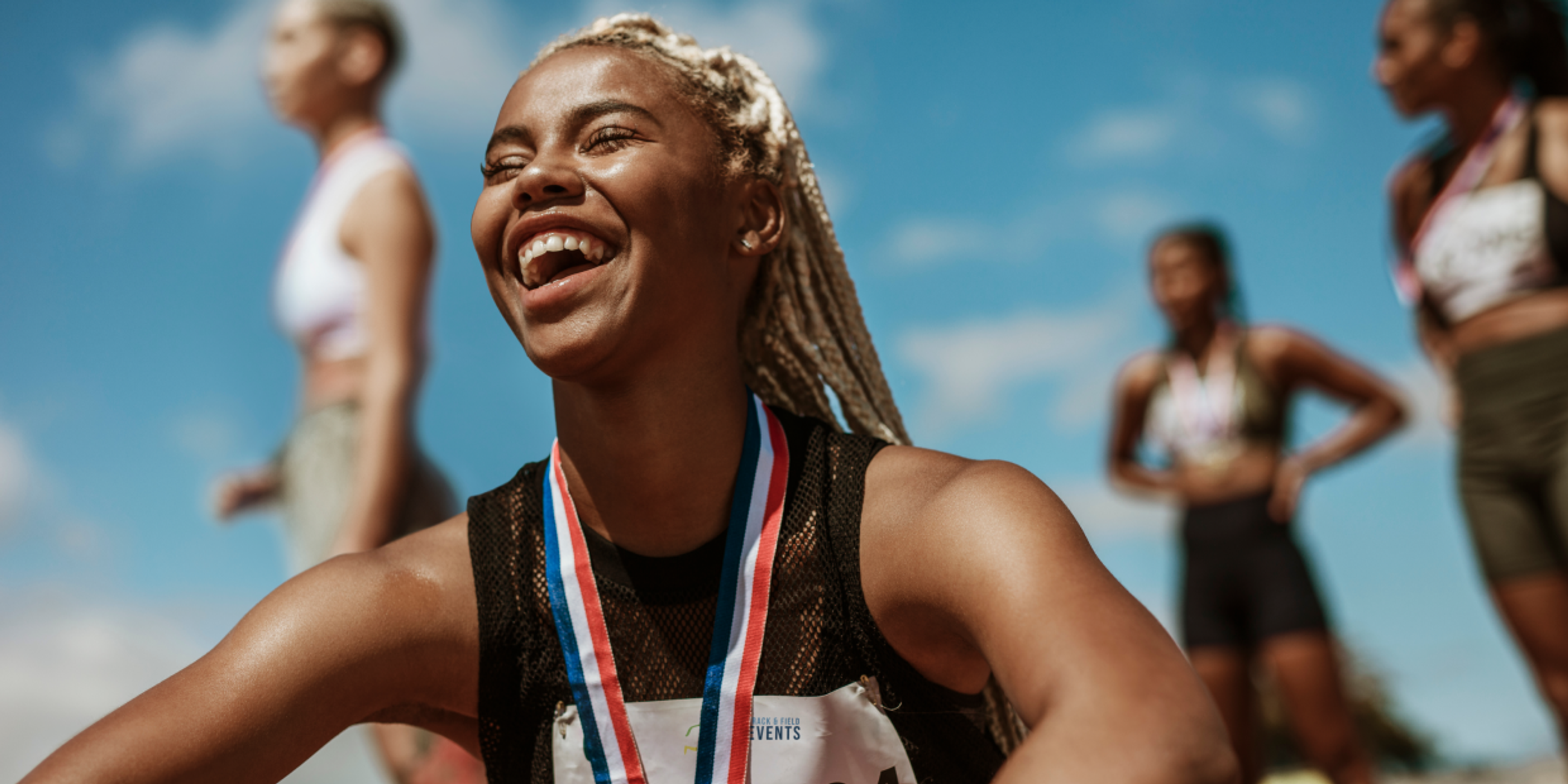 Female runner smiling and celebrating after finishing her marathon race.