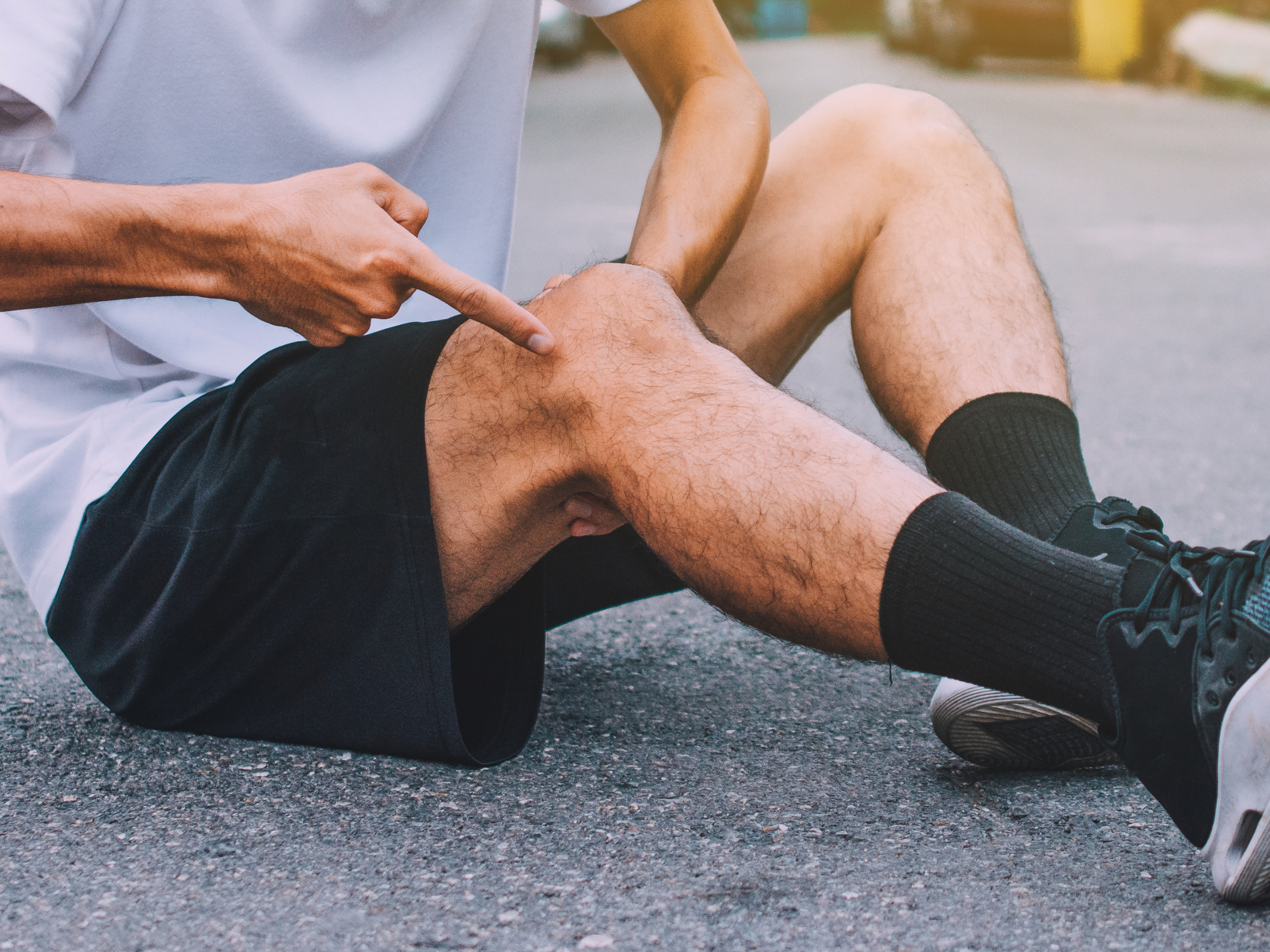 Male runner with IT band syndrome sitting on the ground.