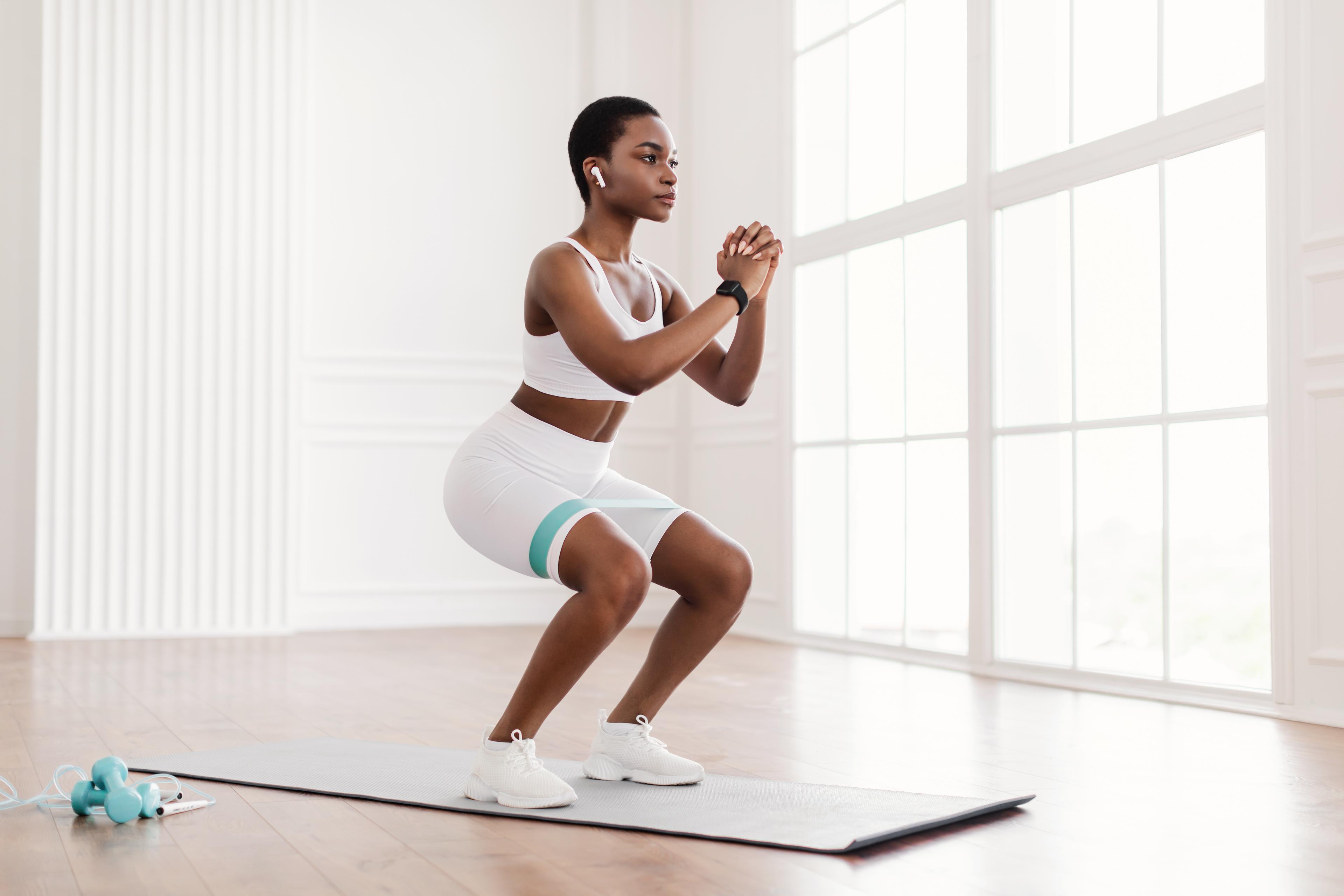 Une femme effectue un squat médian des fessiers comme exercice pour le syndrome de la bandelette ilio-tibiale.