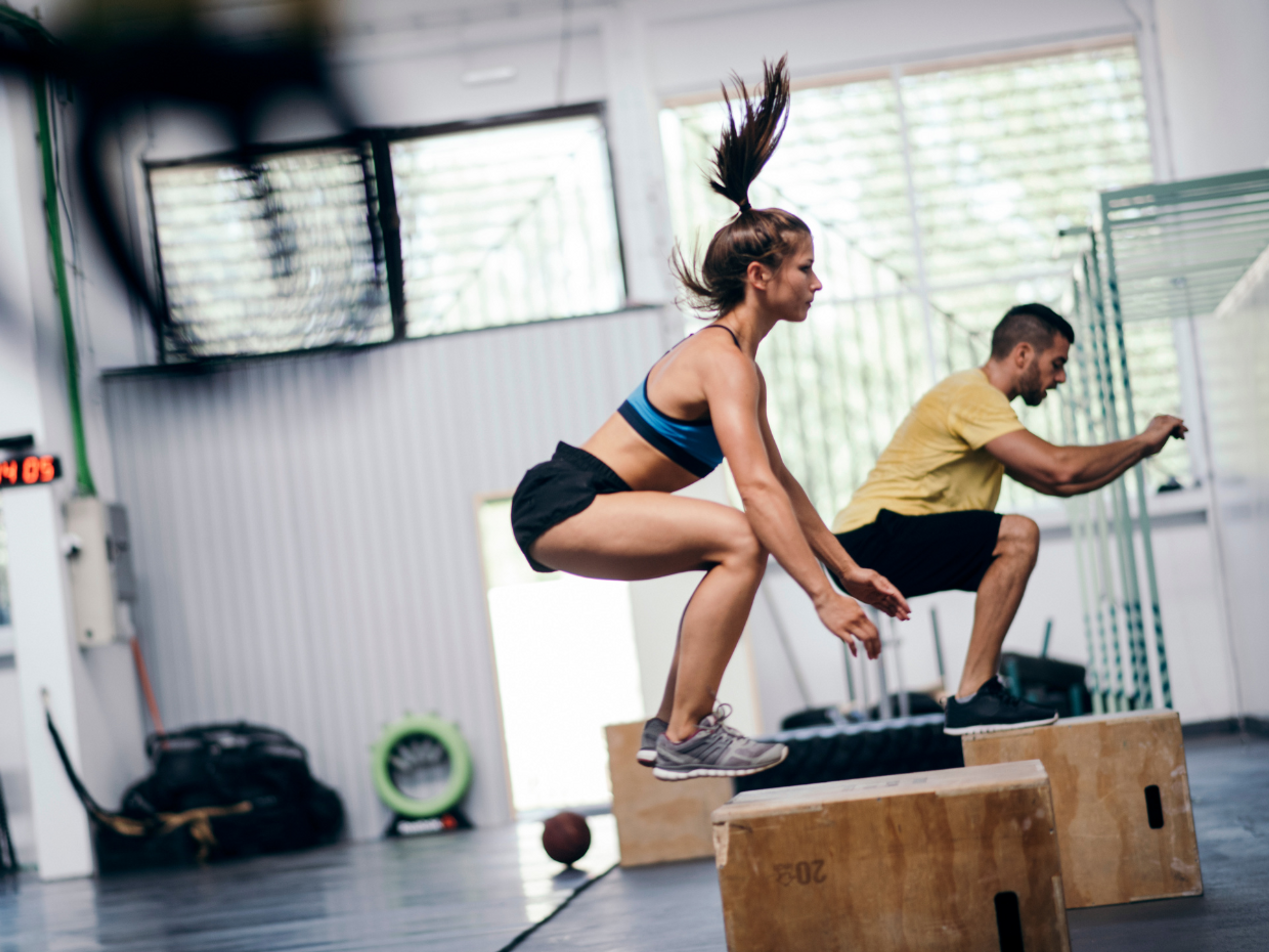 Man and woman performing box jumps as an exercise for patellar tendonitis.