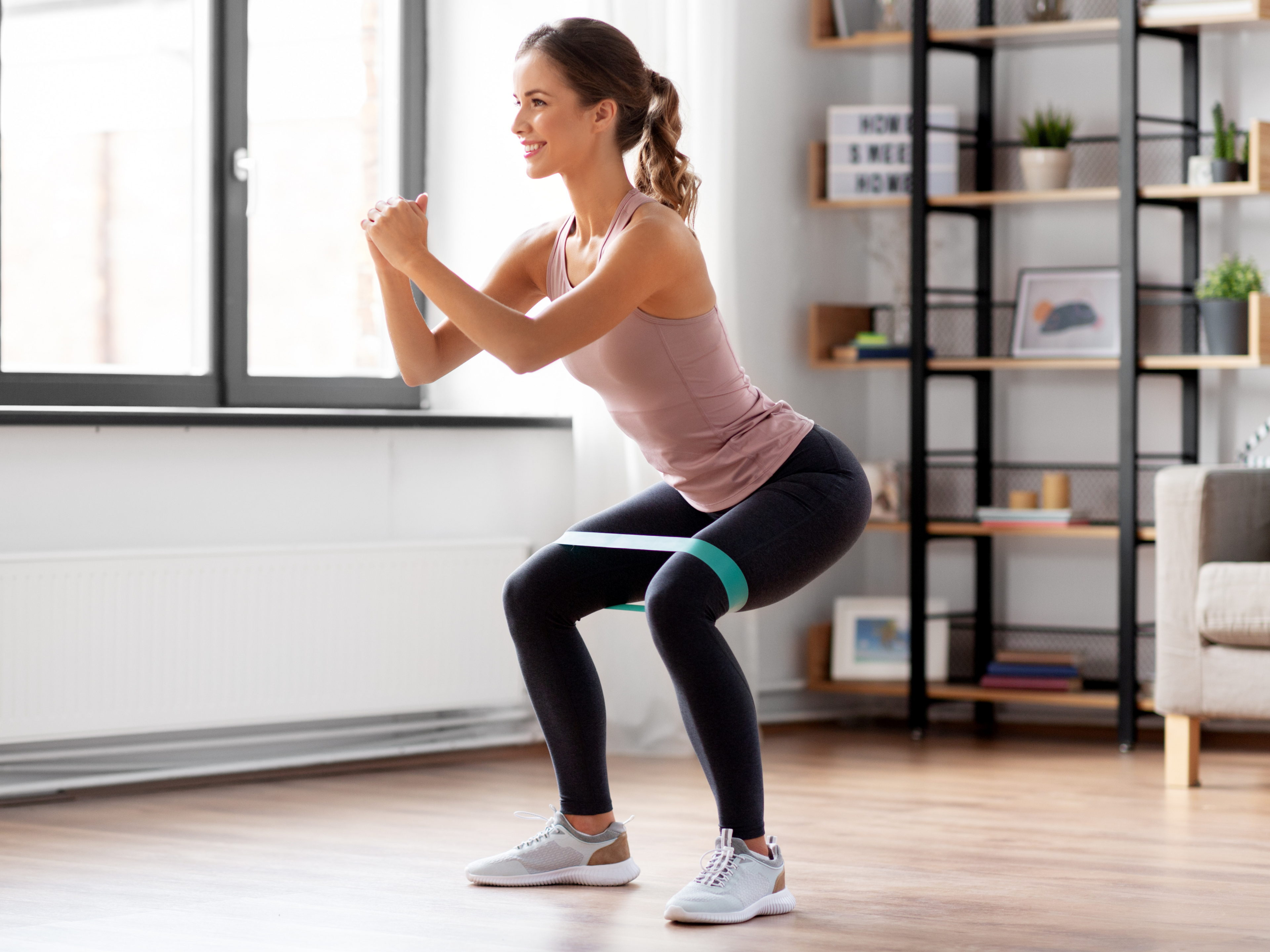 Femme effectuant un squat au poids du corps avec un miniband.