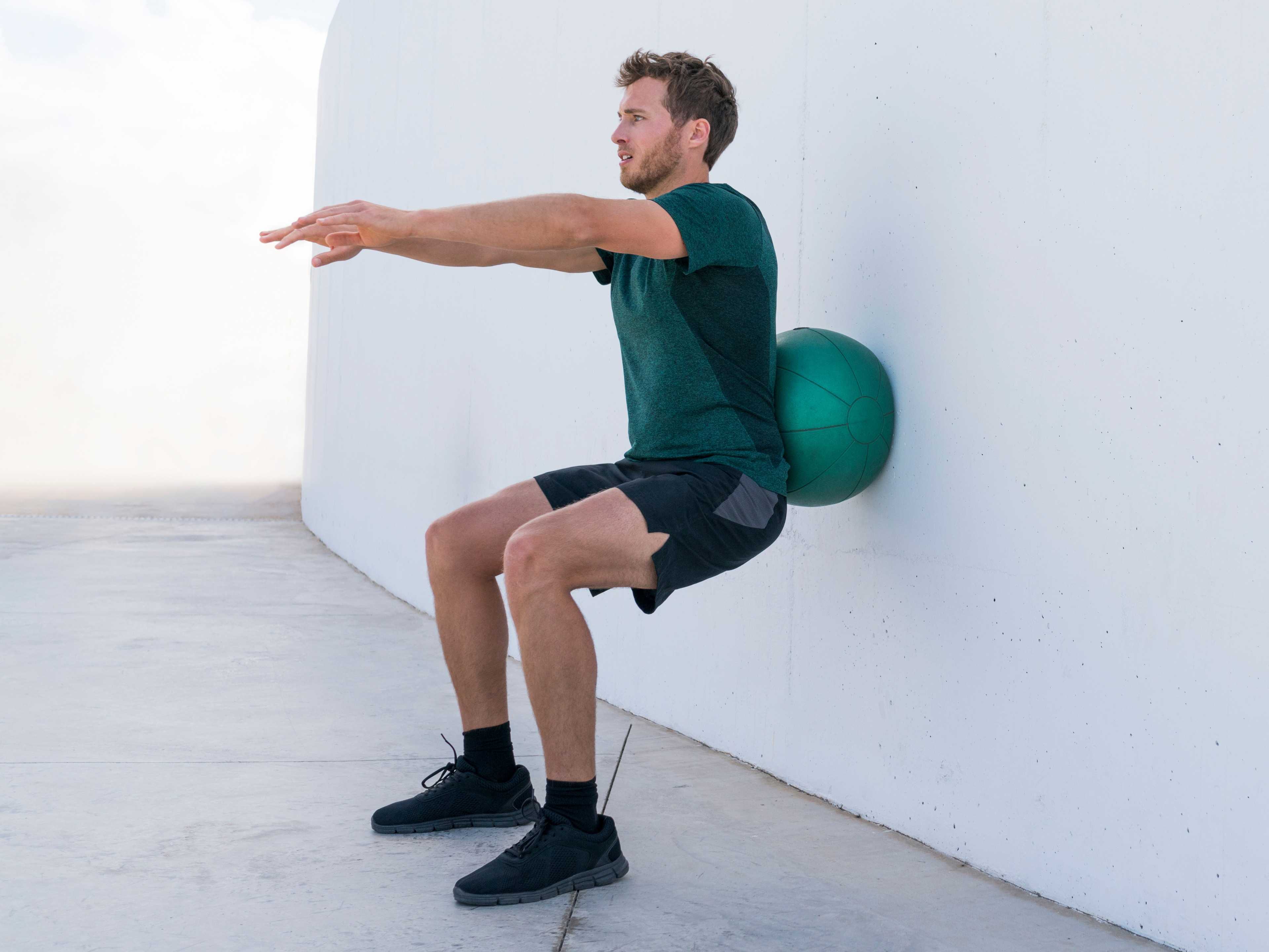 Man performing stability wall squat. 