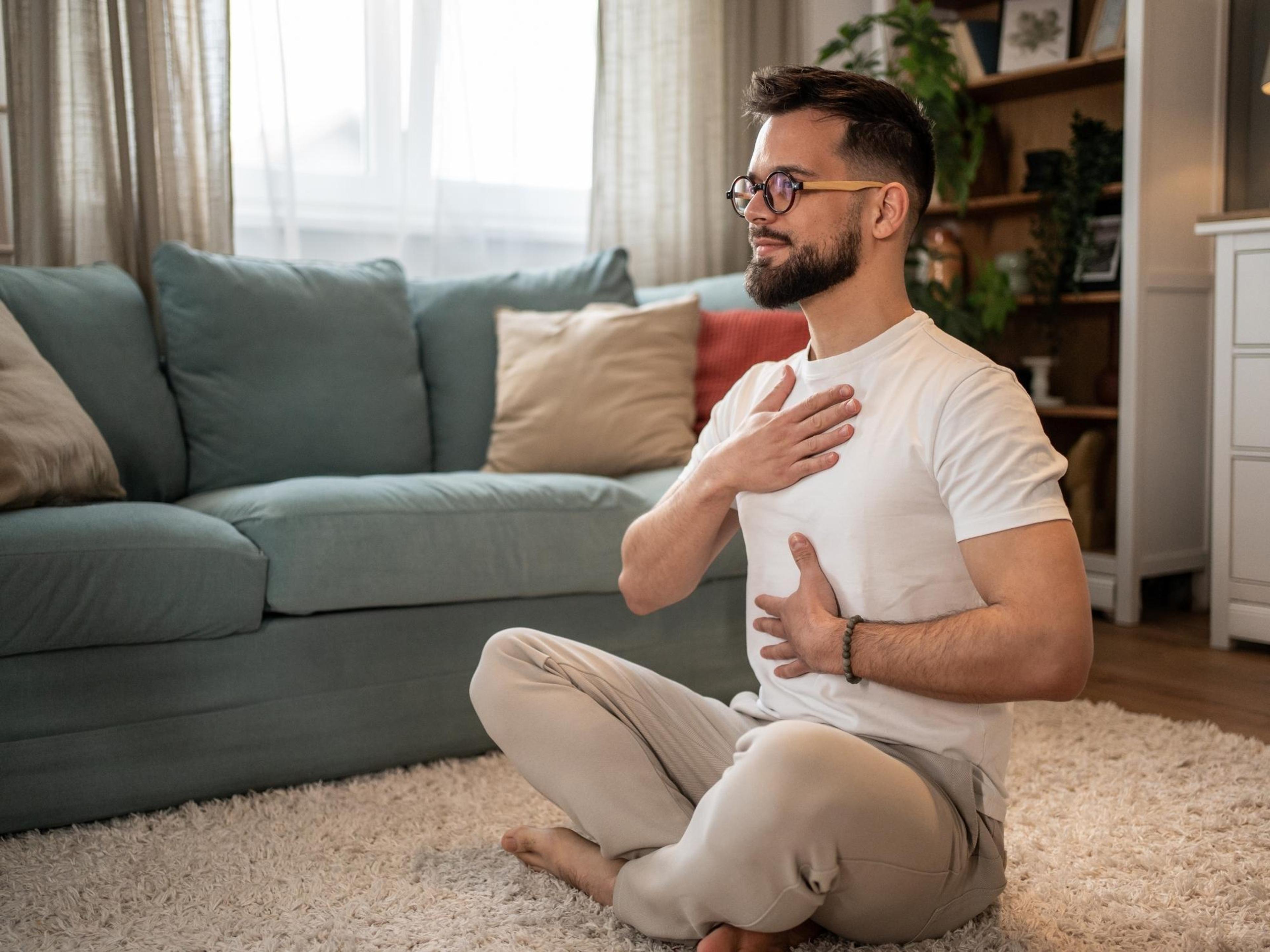 A man practicing belly breathing with one hand on his chest and the other on his stomach.
