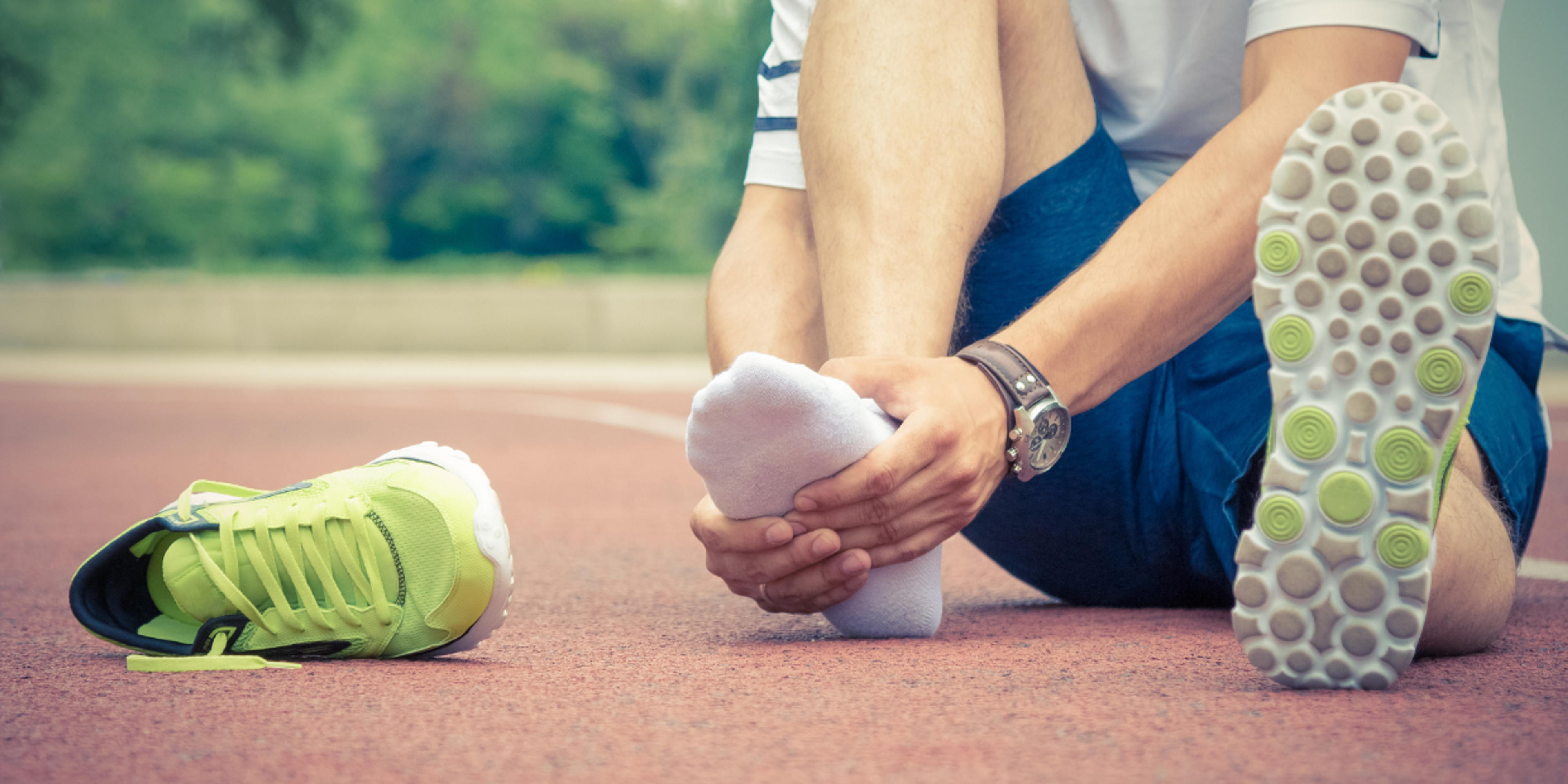 Runner holding his foot due to plantar fasciitis pain
