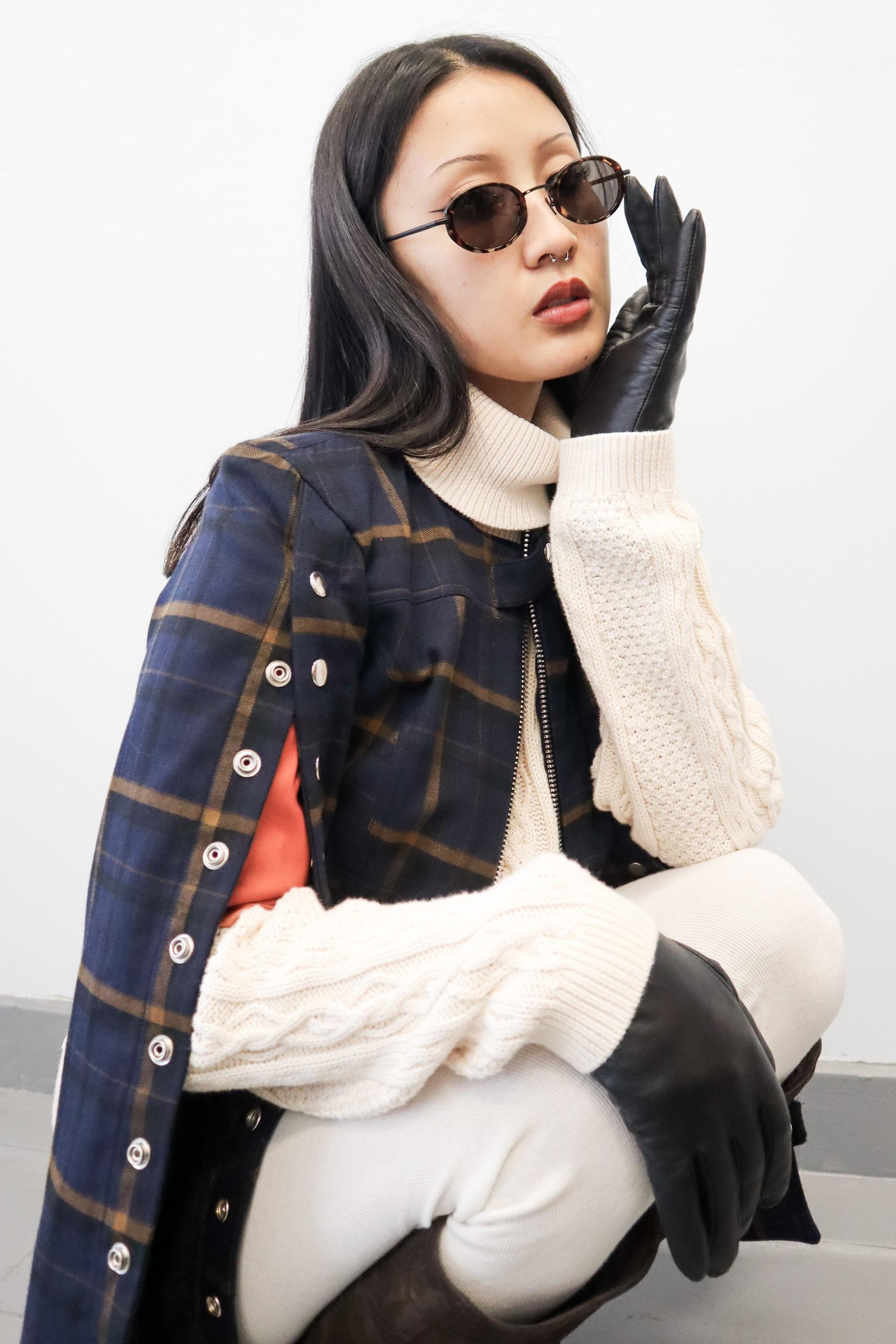 Model in sunglasses, a checked cape and long black gloves.
