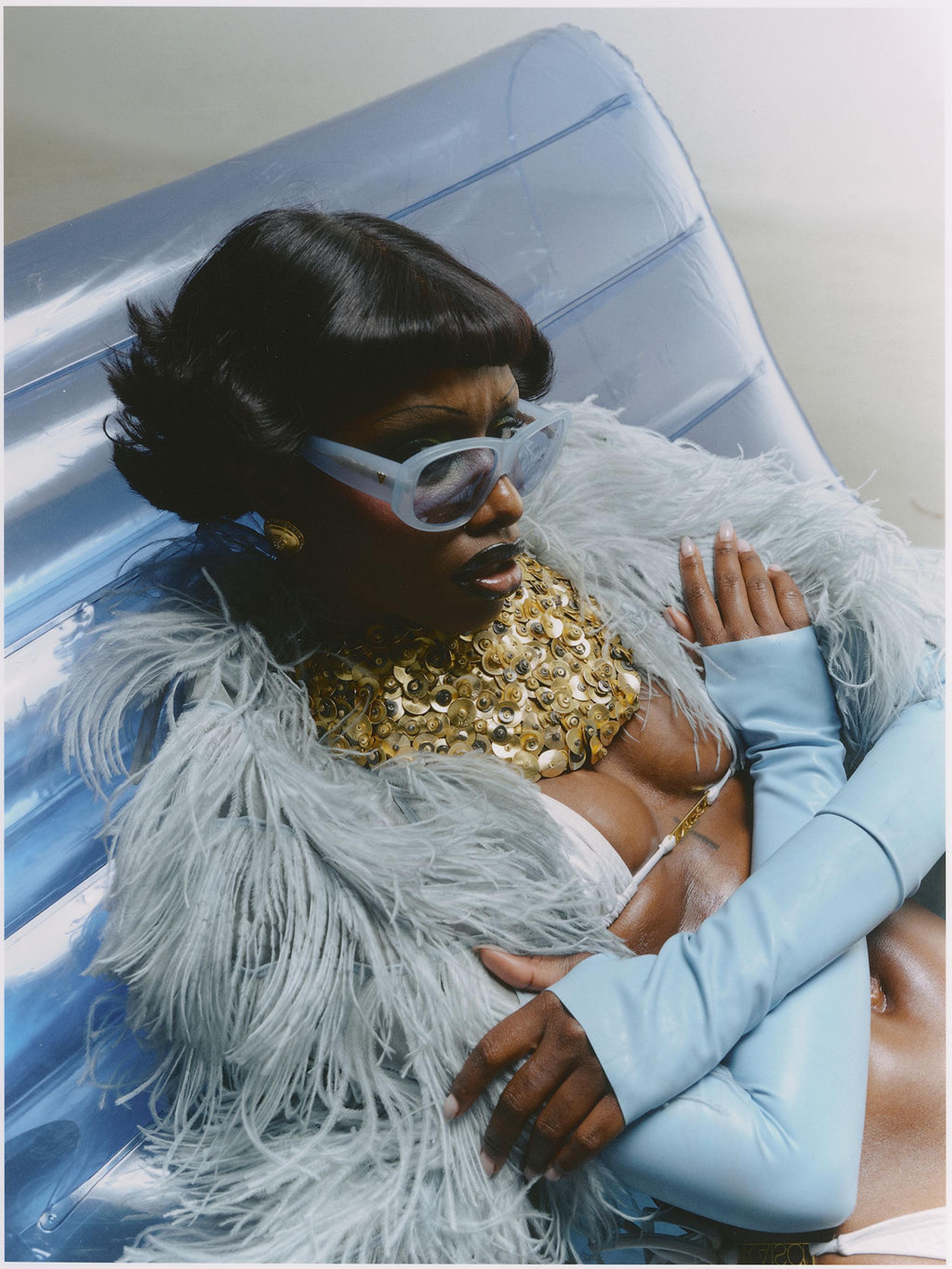 Dark skin model wearing blue sunglasses on a pool float up-close.